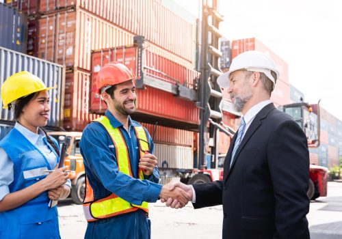 Engineer and foreman  shake hand at container yard near with a forklift., Logistics concept inside the shipping, import, and export industries.