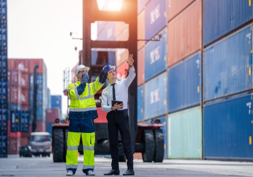 Manager and professional container yard workers checking stock for loading in the container yard warehouse,Logistic shipping yard business.